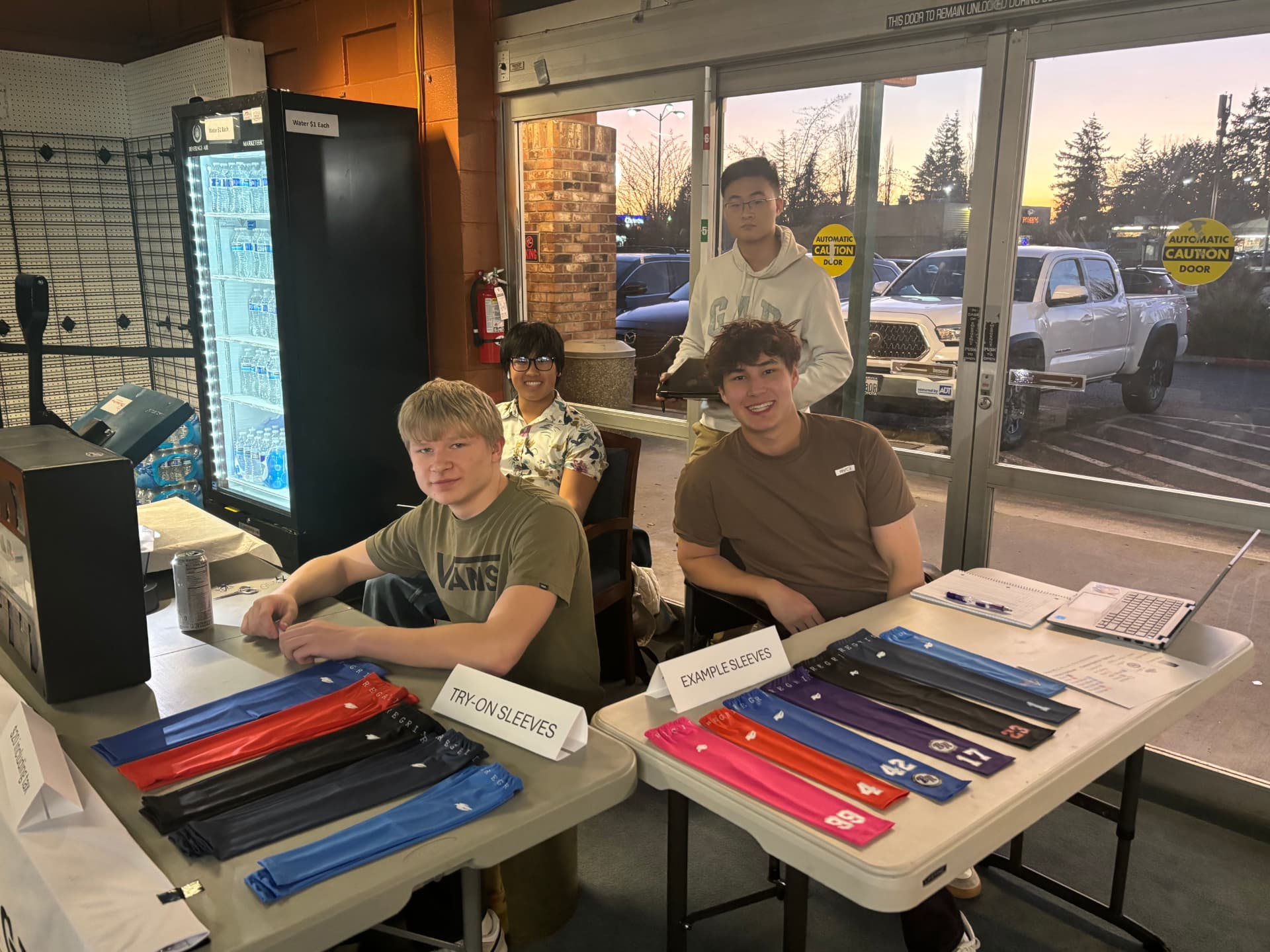 The Peregrine team running an arm-sleeve sale with try-on and example sleeves on the table